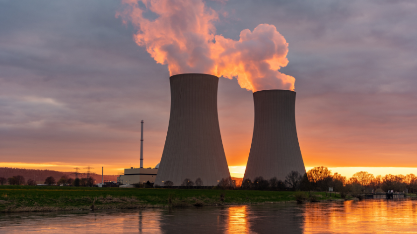 Nuclear power plant smoke stacks set against the dawn sky next to a river