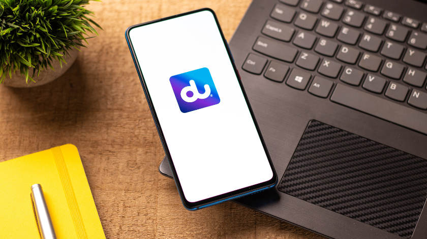 UAE provider du logo projected onto a mobile phone resting atop a black laptop on a desk