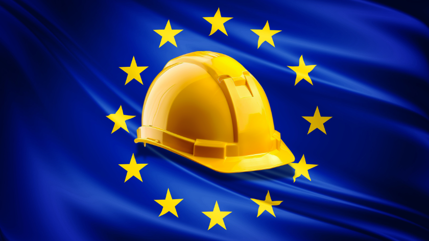 A yellow hardhat set in front of the flag of the EU