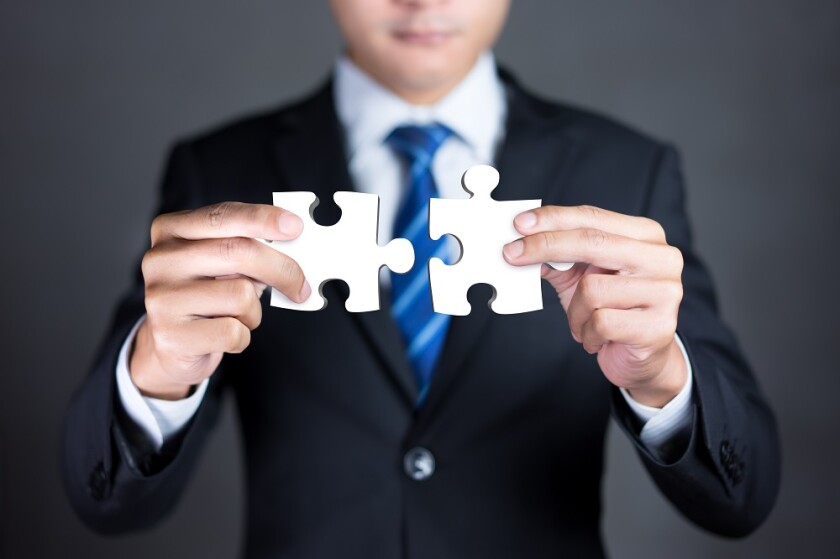 Businessman hands connecting puzzle pieces representing the merg