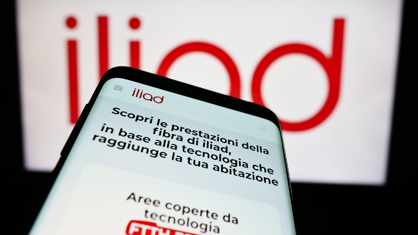 Mobile phone with website of telecommunications company Iliad Italia S.p.A. in front of business logo. Focus on top-left of phone display.